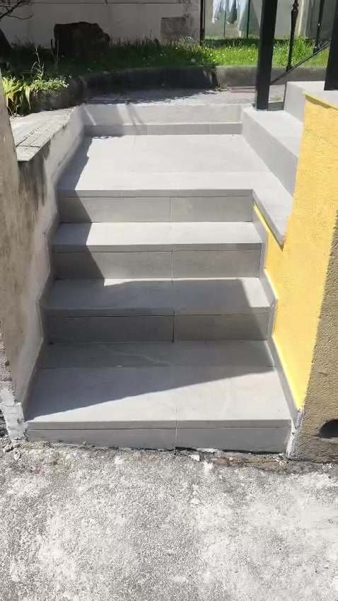 Escalera y terraza exteriores con suelo de gres gris y barandilla de forja