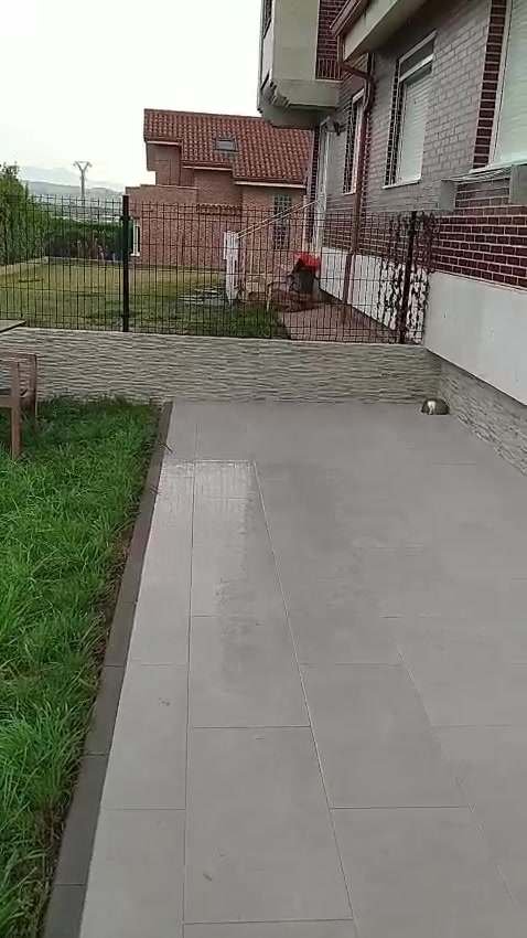 Patio y terraza de porcelánico con murete de piedra en una vivienda unifamiliar