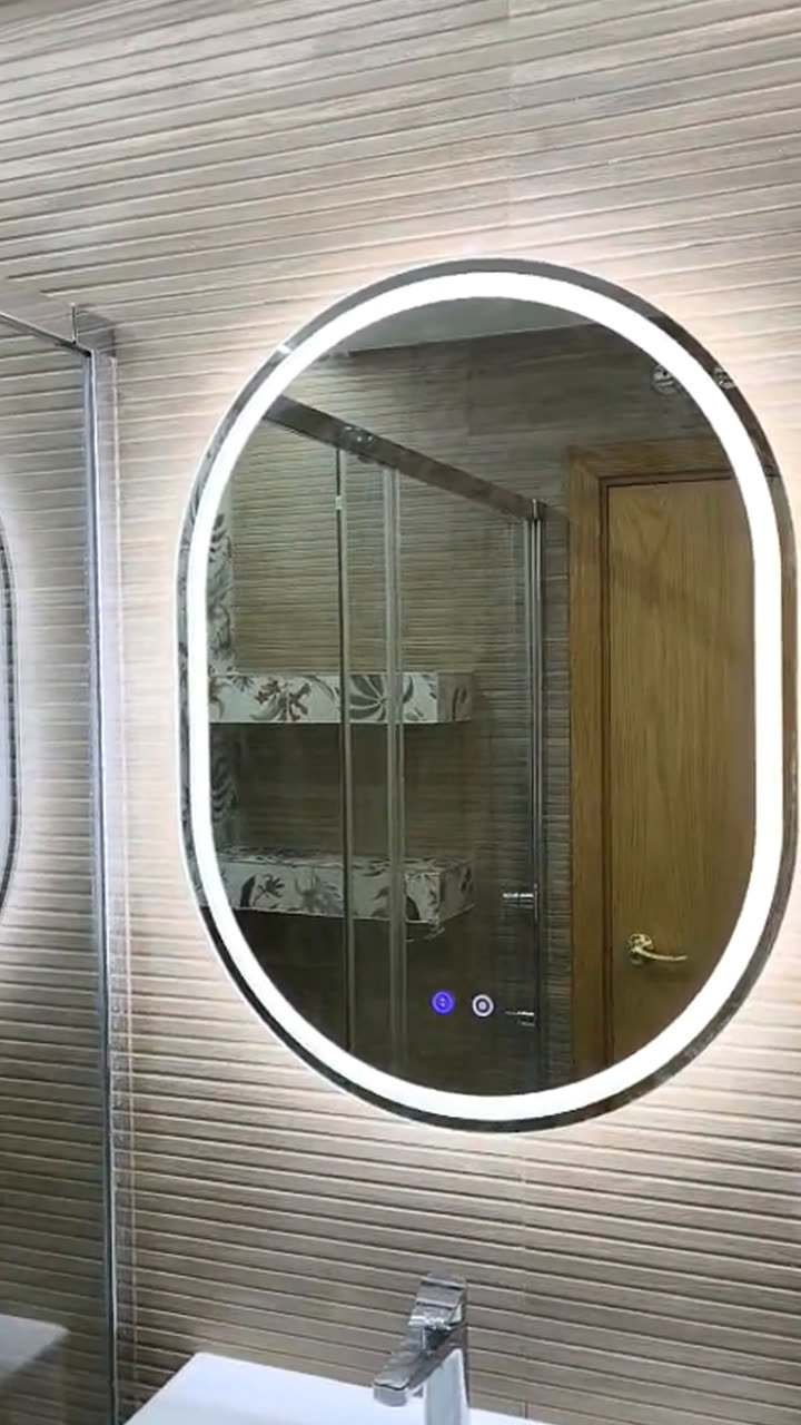 Vídeo de una reforma de baño: espejo ovalado con luz, pared de azulejo con relieve, ducha con mampara y pared de hojas estampadas, y lavabo blanco