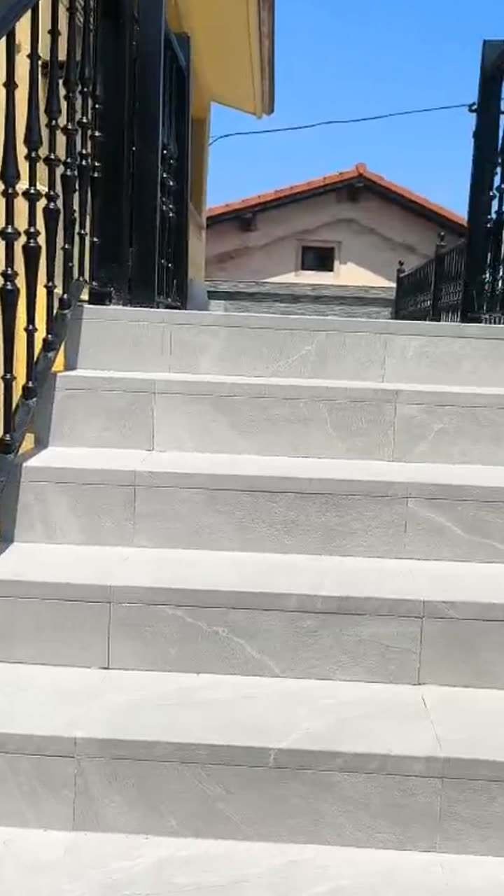 Vídeo de una terraza y unas escaleras exteriores reformadas, con peldaños y suelo grises y barandilla de barrotes negros
