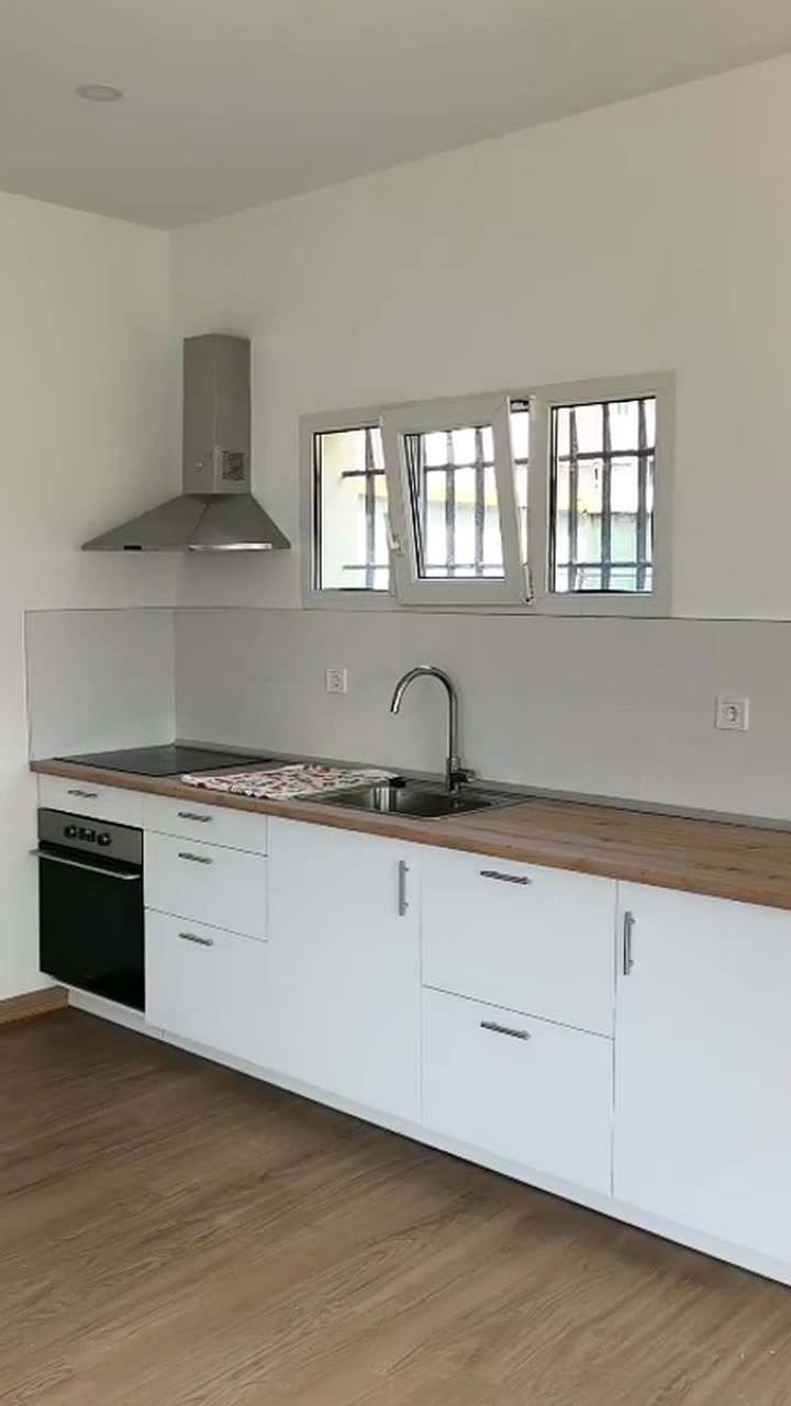 Vídeo de una reforma integral de vivienda: estancias con suelo de madera, cocina blanca con campana, puertas de madera y ducha con mampara de cristal