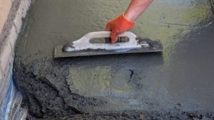 Home 7 Aplicador extendiendo con llana un mortero continuo sobre el suelo, el paso previo al acabado de microcemento